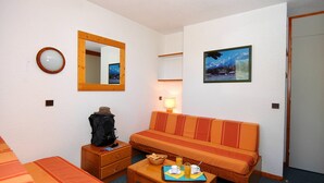 Ein Hotelzimmer mit einer Couch, einem kleinen Tisch mit Frühstück, einer Lampe, einem Spiegel und einem Bild an der Wand.