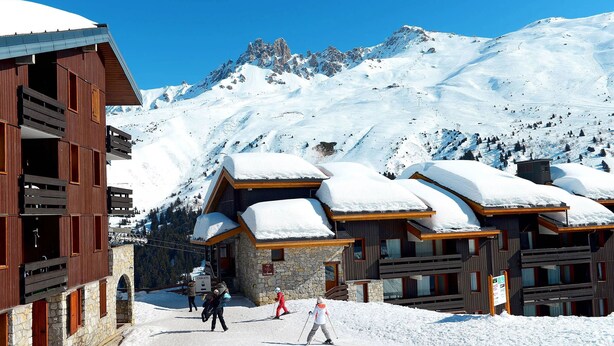 Une station de montagne enneigée, avec des bâtiments en bois et des pistes de ski.