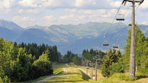 Une route de montagne avec un télésiège et un paysage boisé.