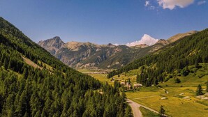 Un paysage montagneux comprenant une vallée, une forêt dense et un petit village avec quelques bâtiments.