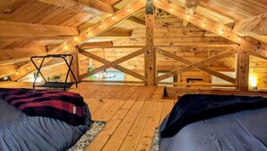 Ein Schlafzimmer im Dachgeschoss mit Holzbalken, einer Schaukel und Blick ins Freie.