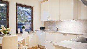 Une cuisine moderne avec des meubles blancs, un évier et une fenêtre donnant sur un quartier résidentiel.