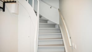 Un escalier blanc avec une rampe et un luminaire fixé au mur.