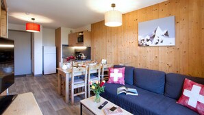 Eine moderne Küche mit Holzausstattung, einem Esstisch mit Stühlen, einer Couch mit Kissen und einem Bild an der Wand.