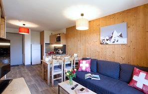 Relax in a cozy living area with a comfortable sofa, dining table, and warm wooden paneling.