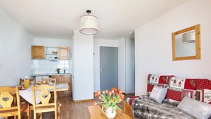 Una sala de estar moderna con un sofá de madera, una mesa de comedor con sillas, y una zona de cocina al fondo.