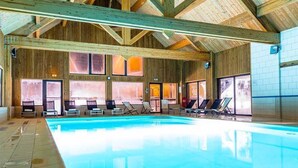 Une grande piscine intérieure avec des poutres en bois et des murs carrelés.