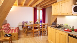 Una cocina acogedora con vigas de madera, una mesa de comedor, sillas, un microondas y un fregadero.