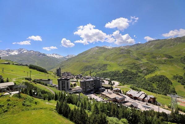 A mountainous landscape with buildings, including a hotel with multiple floors and a ski lift visible.