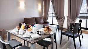 A modern hotel room with a dining area, breakfast setup, and a view of snow-capped mountains. - Sleeps 6 | 1-Bedroom | Hidden Gem in Les Menuires (Les Menuires)