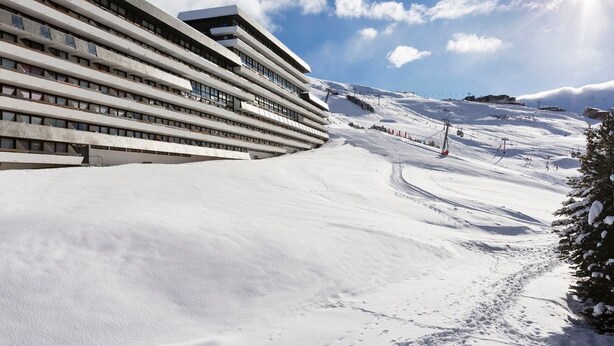 A modern building with a sloped roof, adjacent to a snow-covered ski slope. - Sleeps 6 | 1-Bedroom | Hidden Gem in Les Menuires (Les Menuires)