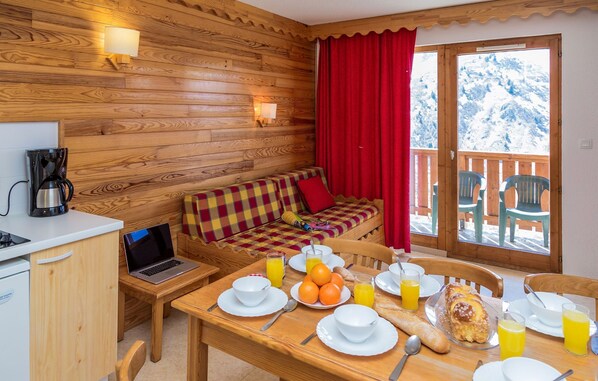 Un accogliente chalet in legno con zona pranzo, un laptop su un tavolo e una colazione preparata con arance, succo e pane.