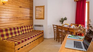 A wooden interior with a checkered sofa, a dining table with chairs, and a laptop on a desk. - 1BR Sleeps 6 | Mountain Escape in Valmeinier! (Valmeinier)