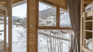 A wooden cabin with a large window offering a view of a snowy landscape and mountains. - Praz-sur-Arly | Sleeps 6 | Never-Ending Thrills (Praz-sur-Arly)