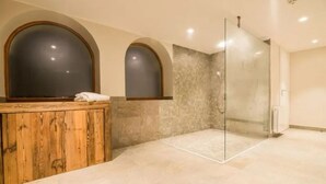 A modern bathroom with a wooden vanity, a glass shower enclosure, and a tiled floor.