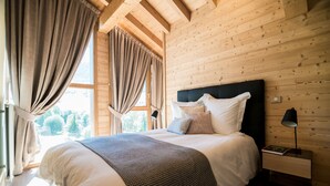 Una stanza con pannelli in legno, un letto grande, un comodino e una finestra con tende.
