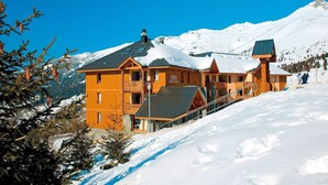 A large wooden lodge with multiple balconies and a ski lift visible.