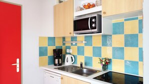 A compact kitchen with a microwave, coffee maker, and sink.