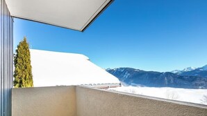 Un balcon offrant une vue sur des montagnes enneigées et un ciel bleu dégagé.