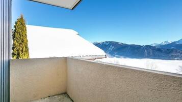 Un balcon offrant une vue sur des montagnes enneigées et un ciel bleu dégagé.