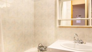 A bathroom with a bathtub, a sink, and a mirror. - Sleeps 7! 2BR Apt| Scenic Living in Valmorel! (La Léchère)
