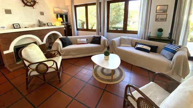 A cozy living room with a fireplace, two sofas, a coffee table, and a ship's wheel decoration on the wall. - Maison Familiale Proche Plage (PYLA SUR MER)