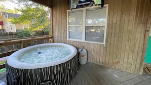 En træterrasse med jacuzzi og et tv monteret på væggen.
