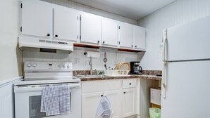 A kitchen with white cabinets, a stove, a sink, and a refrigerator. - Premier League Pad - with Free Parking, Heat & AC (Manchester)
