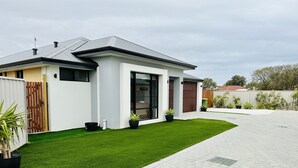 A modern two-story house with a well-maintained lawn, a driveway, and a fenced backyard. - New 5 Bedroom Home 1km from the Beautiful Busselton Beaches  (Geographe)