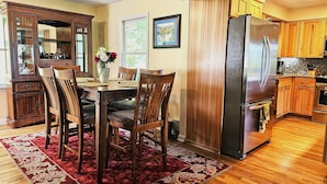 A modern kitchen with wooden cabinets, a stainless steel refrigerator, and a dining area with a red patterned rug. - Gorgeous, cozy, private retreat - Hot tub, views, CLOSE TO EVERYTHING. 43 acres! (Banner Elk)