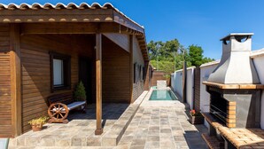 A wooden building with a covered patio, a stone pool, and a barbecue area. - Rural House 'La Dehesa2' in Toledo with Private Pool, Wi-Fi, and Air Conditioning (Cobisa)