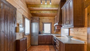 A wooden interior with a kitchen area including cabinets, a refrigerator, and a sink. - Rural House 'La Dehesa2' in Toledo with Private Pool, Wi-Fi, and Air Conditioning (Cobisa)