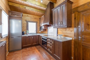Una cocina con armarios de madera, un refrigerador de acero inoxidable y piso de baldosas.