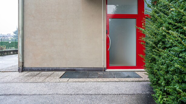 A building with a red door, a beige wall, and a green hedge. - Apartment 'Trento Degasperi 16' with Wi-Fi (Trento)