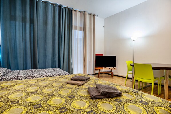 A hotel room with a bed, a desk, a chair, and a TV.