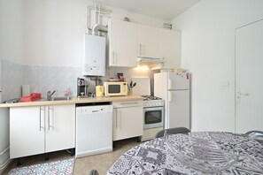 A compact kitchen with white cabinets, a microwave, a stove, a dishwasher, and a refrigerator. - Holiday Apartment "À Luchon" near the Slopes with Balcony and Wi-Fi (Bagnères-de-Luchon)
