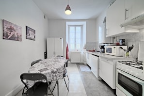 Una cocina compacta con una mesa de comedor, sillas, estufa, microondas y refrigerador.