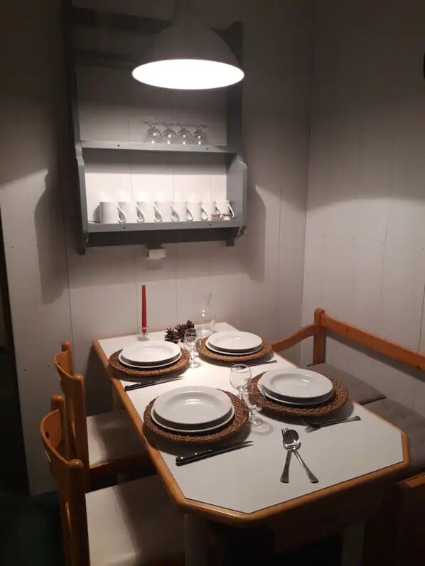 A dining table set with plates, cutlery, and a candle, with a shelf above holding cups and glasses. - Apartment 'Tilia - Avoriaz' with Mountain View and Balcony (Avoriaz)