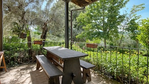 An outdoor patio with a wooden table and benches, surrounded by a metal fence and lush greenery. - Agriturismo "Il Grappolo E La Rosa - Sagrantino" with Shared Pool, Private Terrace, and Wi-Fi (Montefalco)