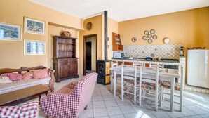 A living room with a sofa, a dining table with chairs, a kitchen area with a stove, and a refrigerator. - Agriturismo "Il Grappolo E La Rosa - Sagrantino" with Shared Pool, Private Terrace, and Wi-Fi (Montefalco)