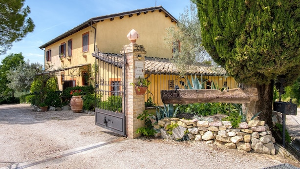 A yellow building with a tiled roof, a stone gate, and a sign reading 'Agriturismo.' - Agriturismo "Il Grappolo E La Rosa - Sagrantino" with Shared Pool, Private Terrace, and Wi-Fi (Montefalco)