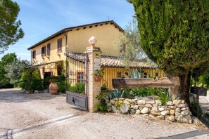 A yellow building with a tiled roof, a stone gate, and a sign reading 'Agriturismo.' - Agriturismo "Il Grappolo E La Rosa - Sagrantino" with shared pool, private terrace, and Wi-Fi (Montefalco)