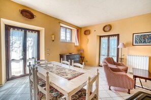 A dining area with a table, chairs, and a checkered sofa. - Agriturismo "Il Grappolo E La Rosa - Sagrantino" with Shared Pool, Private Terrace, and Wi-Fi (Montefalco)