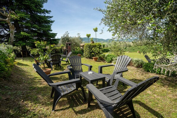 An outdoor seating area with chairs and a table, surrounded by greenery and a view of hills. - Agriturismo "Il Grappolo E La Rosa - Sagrantino" with shared pool, private terrace, and Wi-Fi (Montefalco)