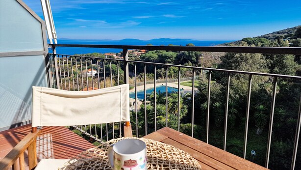 A balcony with a view of a pool and surrounding greenery.