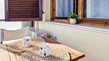 Ein Holztisch mit gewebten Tischsets, zwei dekorative Tassen, ein kleiner Topfpflanze und ein Fenster mit Holzhörnern.