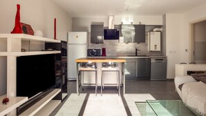 Una cocina moderna con horno empotrado, un comedor con mesa de vidrio y una sala de estar con sofá.