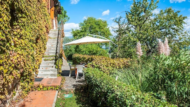 A stone staircase leading to a covered outdoor seating area with a white umbrella, surrounded by lush greenery and trees. - Holiday Home 'La Ripa - Appartamento I Nidi' with Shared Pool, Garden & Wi-Fi (San Gimignano)