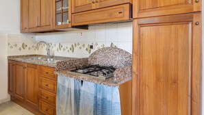 A kitchen with wooden cabinets, a granite countertop, a gas stove, and a stainless steel sink.
