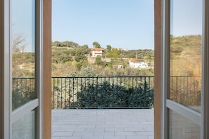 A balcony with a view of a hilly landscape, a green metal fence, and a tiled floor. - Apartment 'Il Faro' with Private Terrace and Private Garden (Celle Ligure)